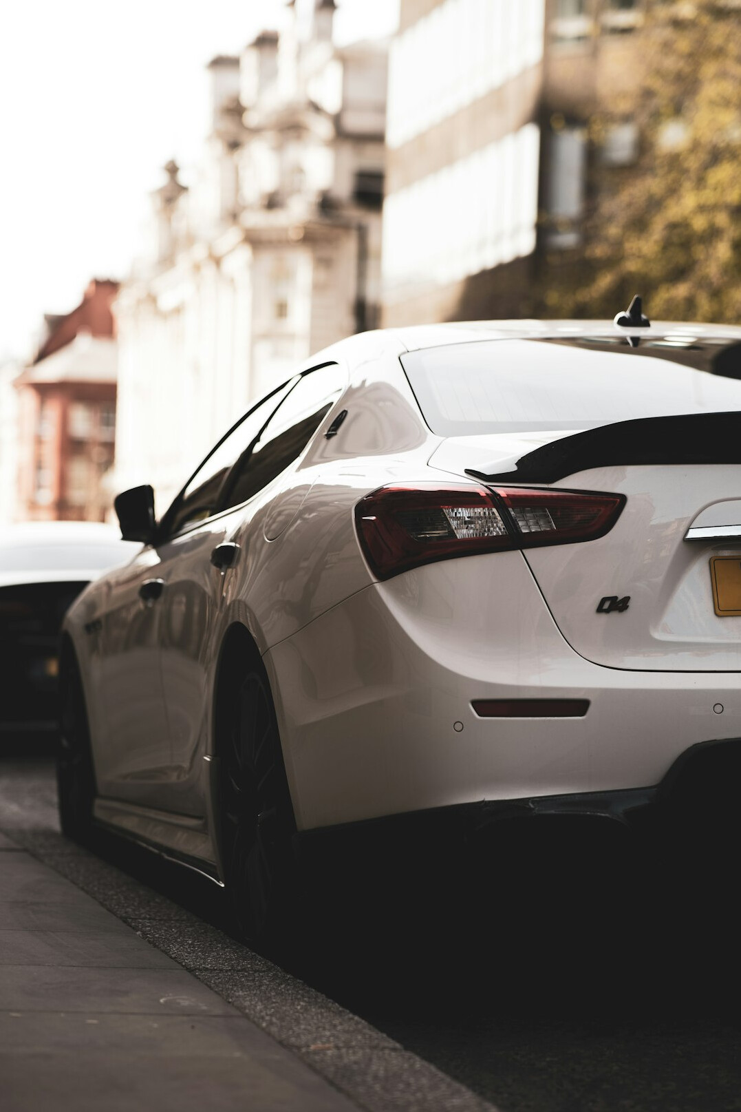 White car parked on a street showing its rear bumper